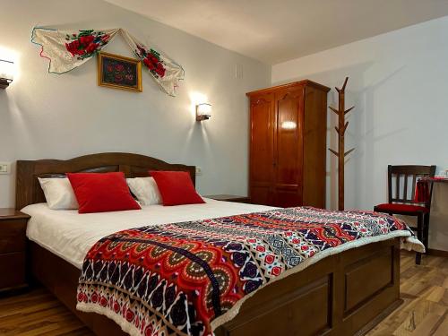 ChişcăuCasa Aurelia的一间卧室配有一张带红色枕头的大床