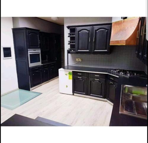 瑟兰Agréable chambre的厨房配有黑色橱柜和木地板