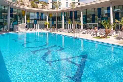佩尼斯科拉阿哥拉Spa度假酒店的一座带椅子的大型蓝色游泳池和一座建筑