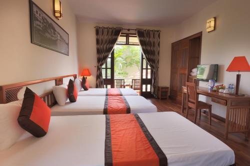 会安Windbell Villa Hoi An的酒店客房设有三张床和一张书桌
