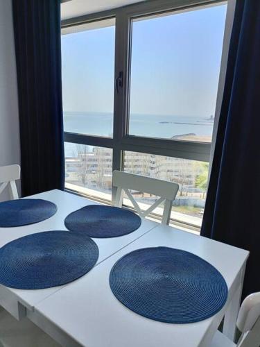 奥林普Olimp sea view的一张白色的桌子,上面有蓝色的板子,有窗户