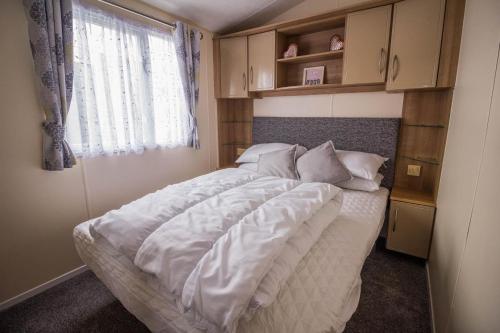 滨海克拉克顿8 Berth Caravan For Hire Near Clacton-on-sea In Essex Ref 26287e的一间卧室配有一张带白色床单的床和一扇窗户。