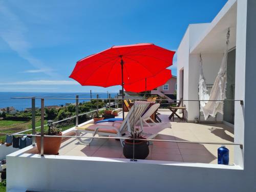 拉日什杜皮库Casa da Ribeira的阳台上的红色遮阳伞和椅子