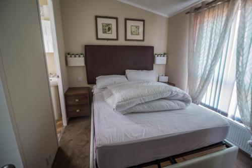滨海克拉克顿Beautiful Caravan At Highfield Grange Holiday Park In Essex Ref 26687p的一间卧室配有一张带白色床单的床和一扇窗户。