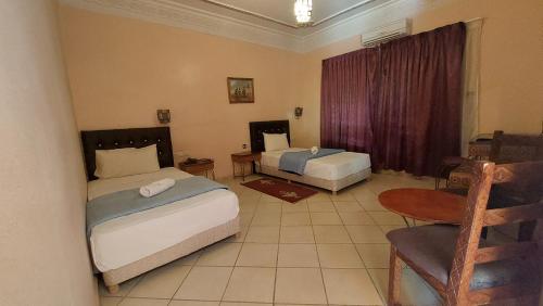 拉希迪耶卡斯巴特阿费杜酒店的一间卧室配有两张床、一张桌子和一把椅子