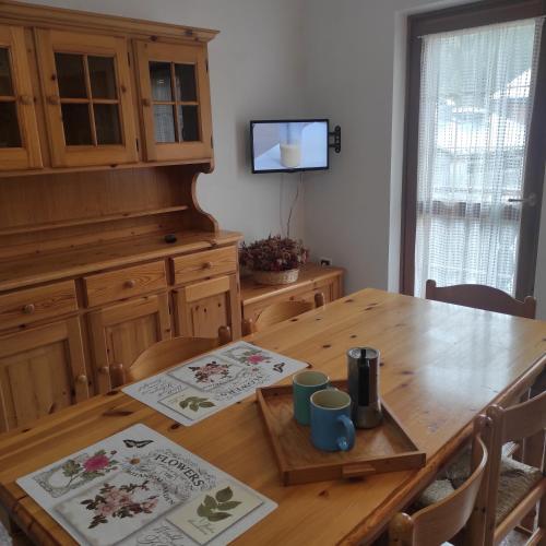 瓦尔迪佐多Casa San Valentino Dolomiti Val di Zoldo的厨房配有木桌、椅子和电视
