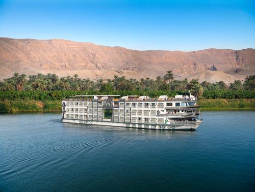 卢克索Sonesta St George Nile Cruise - Luxor to Aswan 4 Nights from Monday to Friday的一艘大船在水面上,背景是群山