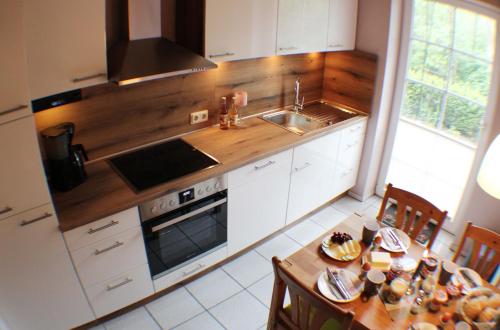 施内沃丁根Ferienwohnung Lüneburger Heide的厨房配有白色橱柜和木制台面