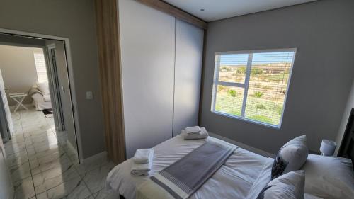 兰格班One Bedroom Unit with Kitchenette in Langebaan Country Estate - Solar Power的一间卧室配有床和带毛巾的窗户。