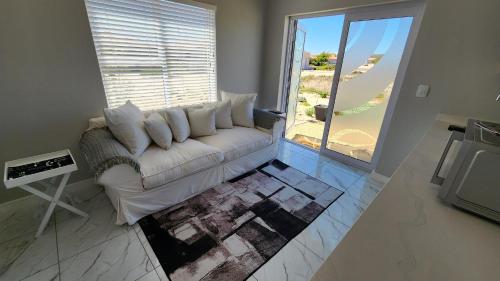 兰格班One Bedroom Unit with Kitchenette in Langebaan Country Estate - Solar Power的客厅设有一张白色沙发,配有大窗户