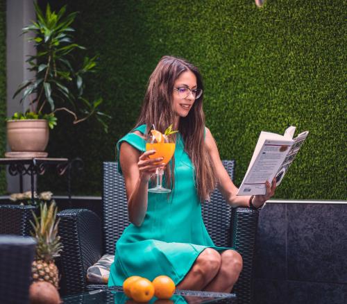 普罗夫迪夫普罗夫迪夫商务酒店的坐在椅子上的女人,一边喝着饮料一边看杂志