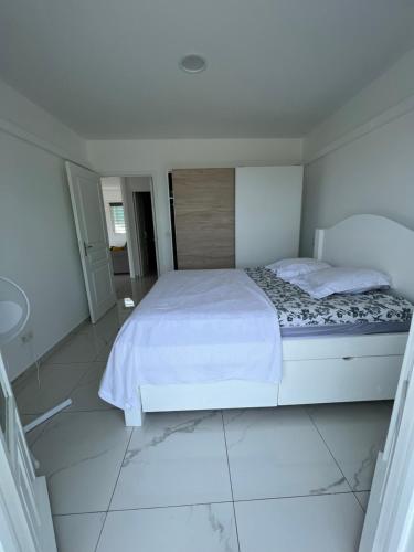 旧阿比唐Villa C的一间白色卧室,配有床和瓷砖地板
