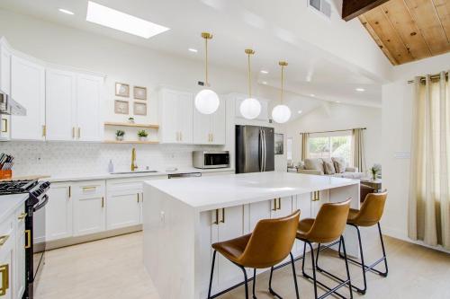 卡梅尔3892 Carmel Pearl home的一间带白色橱柜的厨房和一个带椅子的厨房岛