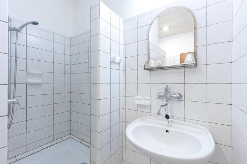比尔森比尔森斯洛文酒店的白色瓷砖浴室设有水槽和镜子