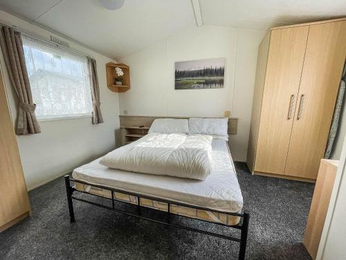 滨海克拉克顿6 Berth Staycation Caravan Nearby Clacton-on-sea In Essex Ref 26254e的一间卧室设有一张床和一个窗口