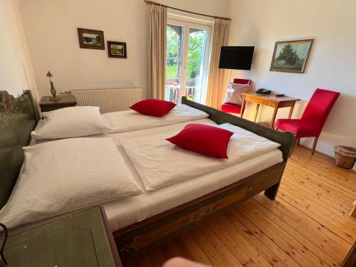 沃尔特湖畔佩莎赫斯特鲁斯尼霍夫兰德豪斯旅馆的一间卧室配有两张带红色枕头的床