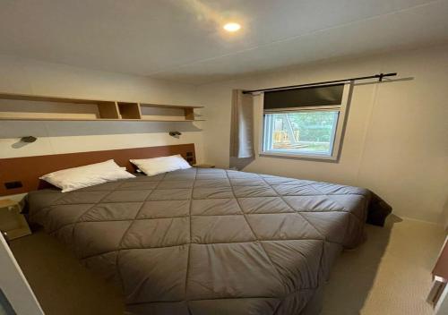 比斯卡罗斯Charmant dans camping 5 étoiles-lac的一间卧室设有一张大床和一个窗户。
