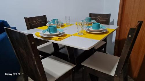 里约热内卢Apartamento Sandy-Zona Sul的桌椅和白色桌子,桌子上摆放着盘子和杯子