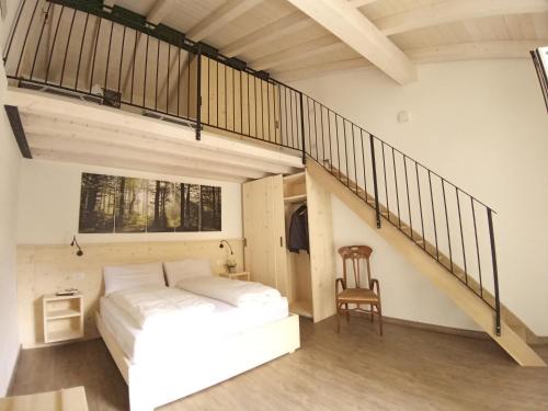 特雷莫西内appartamenti Residenza 1928的卧室配有白色的床和楼梯。