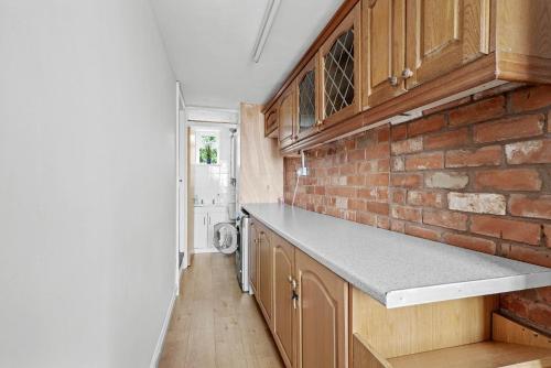 BengeworthWheelbarrow Cottage的厨房配有木制橱柜和砖墙