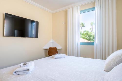 兹奇隆亚科夫Midrahov Luxury Apartment的一间卧室设有一张床、电视和窗户