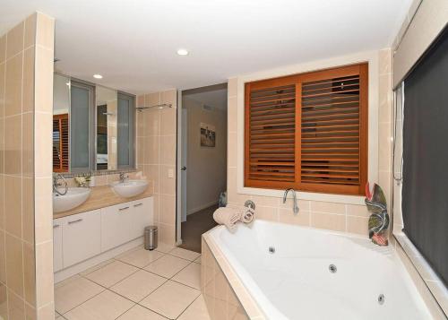 赫维湾Luxurious Beachfront Apartment的带浴缸和两个盥洗盆的大浴室