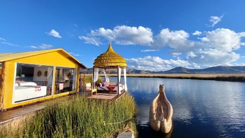 普诺Uros Lodge Perú的河边的黄色房子,设有凉亭