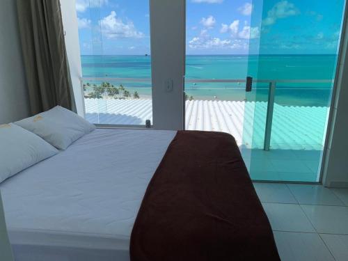马拉戈日Pousada Alto do Cruzeiro的一间卧室配有一张床,享有海滩美景