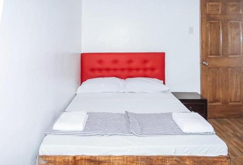 宿务Magabelle Guesthouse的一张红色床头板的床