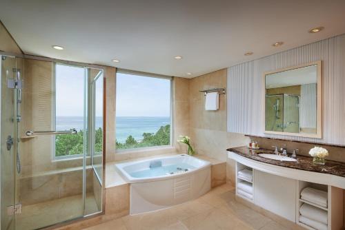 西归浦市济州岛新罗酒店的一间带浴缸和淋浴的浴室以及窗户。