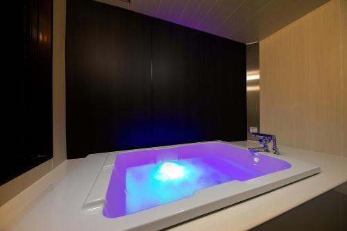 尼崎市Hotel Benkyo Beya Amagasaki的浴室配有紫色灯浴缸