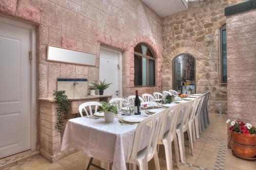 萨法德בראשית - סוויטות בוטיק בצפת העתיקה - Beresheet - Boutique Suites in the Old City的一间带长桌和白色椅子的用餐室