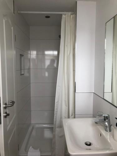 维特Pension "Strandhotel"的白色的浴室设有水槽和淋浴。