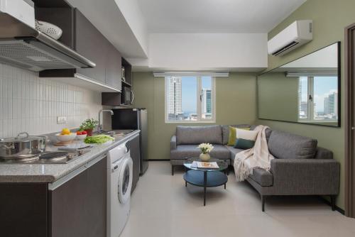 马尼拉The Suites at Torre Lorenzo Malate - Managed by The Ascott Limited的厨房以及带沙发和桌子的客厅。
