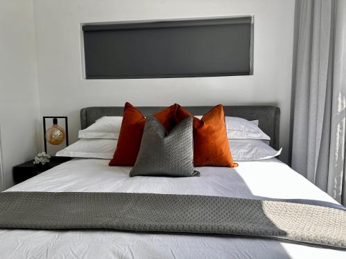 约翰内斯堡Stylish Executive Apartment with Power Backup的一张带橙色和灰色枕头的床