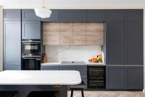 伦敦ALTIDO Spectacular house with private garden的厨房配有蓝色橱柜和白色桌子