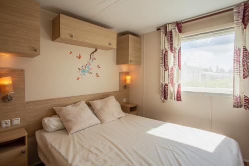 弗雷瑞斯Mobil Home dans camping Frejus的卧室配有白色的床和窗户。