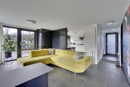 拉纳肯Vijverzicht的一间带黄色沙发的客厅和一间厨房