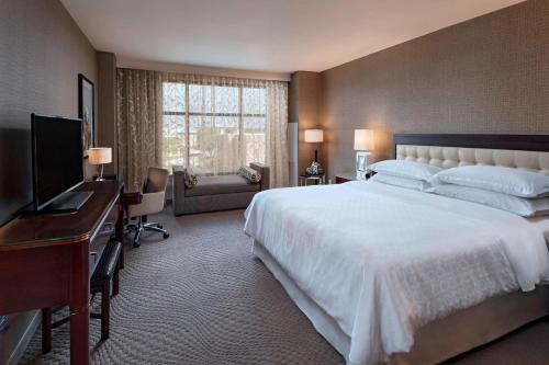 乔治城喜来登乔治敦会议中心酒店 的一间卧室配有一张大床、一张书桌和电视。
