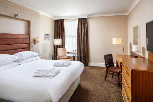 切尔滕纳姆Delta Hotels by Marriott Cheltenham Chase的酒店客房设有一张大床和一张书桌。