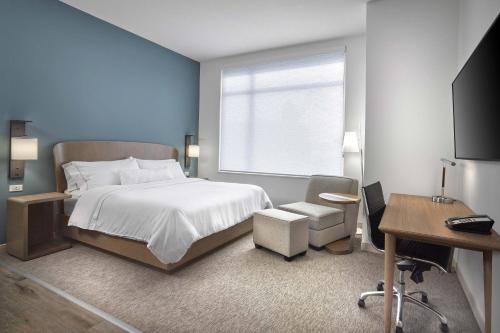 汉普顿Element Hampton Peninsula Town Center的一间卧室配有一张床、一张书桌和一个窗户。