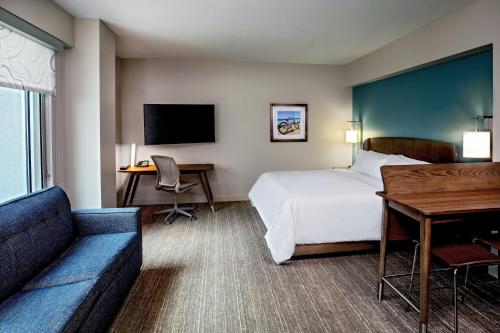 汉普顿Element Hampton Peninsula Town Center的酒店客房配有一张床、一张沙发和一张书桌。