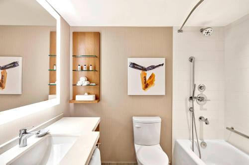 卡尔加里Delta Hotels by Marriott Calgary Downtown的浴室配有盥洗盆、卫生间和浴缸。