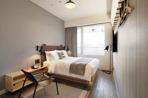 东京MOXY Tokyo Kinshicho的一间卧室配有一张床、一张书桌和一个窗户。