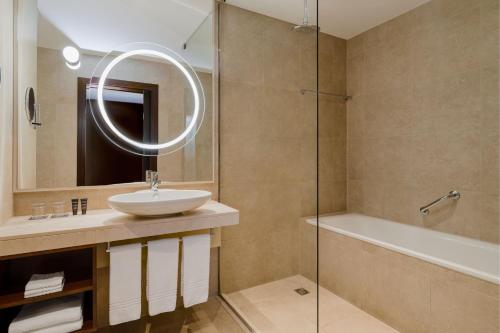 波兹南波兹南喜来登酒店的浴室配有盥洗盆、镜子和浴缸