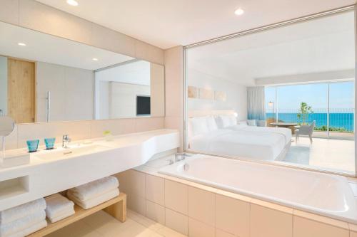 宫古岛IRAPH SUI, a Luxury Collection Hotel, Miyako Okinawa的带浴缸的浴室和1间带1张床的卧室