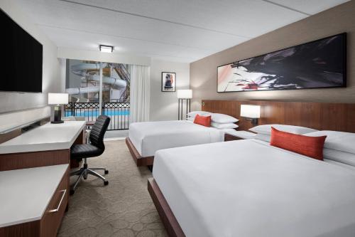 绿湾Delta Hotels by Marriott Green Bay的酒店客房设有两张床、一张桌子和一台电视。