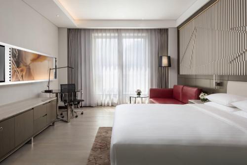 天津天津陆家嘴万怡酒店的酒店客房设有一张大床和一张红色椅子。