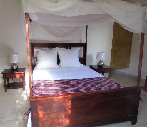 MbodièneWouroBa的一间卧室配有一张带2个床头柜的大型木床