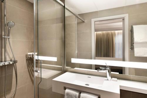 索尔纳AC Hotel by Marriott Stockholm Ulriksdal的一间带水槽、淋浴和镜子的浴室